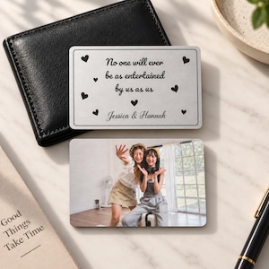 May include: A rectangular metal wallet card featuring the black text "No one will ever be as entertained by us as us" and "Jessica & Hannah" surrounded by small black hearts, paired with a second card displaying a color photograph of two people.