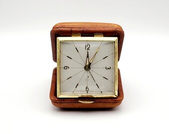 Very pretty travel alarm clock in leather case, from the Jaz brand. Alarm clock, clock, pendulum.