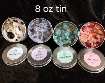 May include: Six 8 ounce tin candles with various crystals and herbs. The candles are labeled with the following scents: Protection, Anxiety Relief, Prosperity, Love Spell.