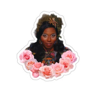 May include: A sticker featuring a woman with dark hair and makeup, adorned with a floral headpiece and a colorful patterned top. The image is framed by a wreath of pink roses, creating a decorative and artistic design.
