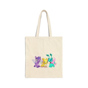 May include: A beige tote bag with a cartoon image of three colorful fairy-like creatures with wings. The creatures are purple, yellow, and blue.