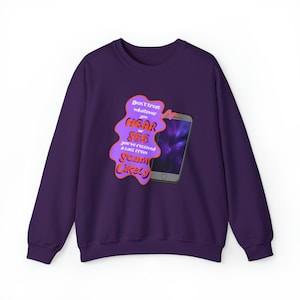 May include: Purple sweatshirt with a graphic of a smartphone and the text "Don't trust whatever you HEAR or SEE you've received a call from SCAM Likely".