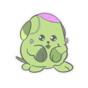 Puede incluir: Un juguete de peluche verde cosido con un cerebro rosa visible, ojos grandes y una lengua que sobresale. El juguete tiene puntadas en los brazos y las piernas y dos alfileres metálicos en la cabeza.