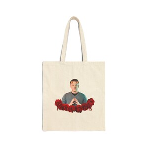 Può includere: Borsa tote color crema con una grafica di una persona con corna da diavolo circondata da rose rosse. Il testo "I'M ALL THE BAD GUYS" è stampato in rosso sotto l'immagine. La borsa ha due manici lunghi.