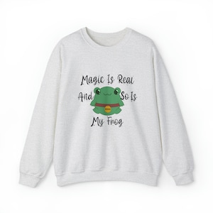 May include: A light grey sweatshirt with a green frog wearing a gold tag that says "BOGO" and the text "Magic Is Real And So Is My Frog".
