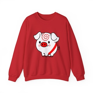 Puede incluir: Una sudadera roja con un diseño de cerdo de dibujos animados. El cerdo es blanco con una nariz roja, una raya roja y un remolino en la cabeza. La sudadera es de color rojo liso.
