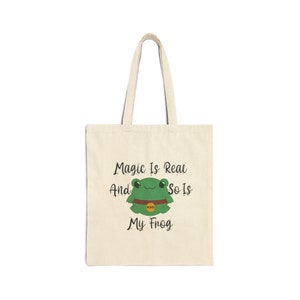 May include: A beige tote bag with a green frog illustration and the text "Magic Is Real And So Is My Frog".