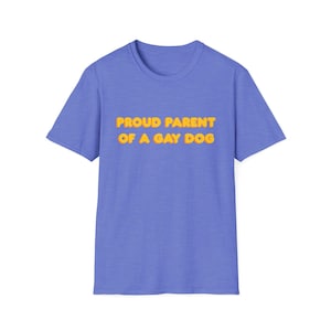 Könnte beinhalten: Ein periwinkleblaues T-Shirt mit dem Text "PROUD PARENT OF A GAY DOG" in gelben Buchstaben mit orangefarbener Umrandung. Das Shirt hat einen Rundhalsausschnitt und kurze Ärmel. Der Text ist mittig auf der Vorderseite des Shirts platziert.