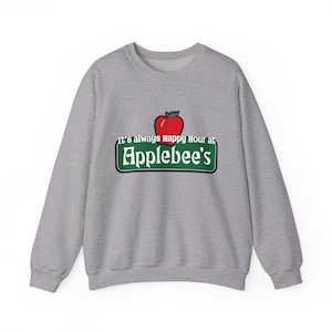 Puede incluir: Sudadera gris jaspeado con el logotipo de Applebee's. El logotipo incluye una manzana roja sobre un rectángulo verde con el nombre del restaurante en blanco. El texto "It's always Happy Hour at" está encima del logotipo.
