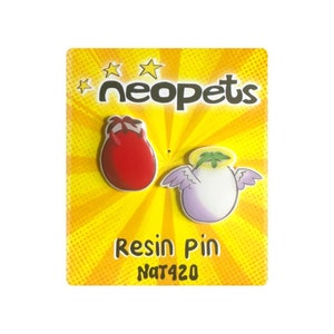 May include: A yellow card with a red and white devil and a purple and white angel on it. The card says "Neopets Resin Pin NAT420".