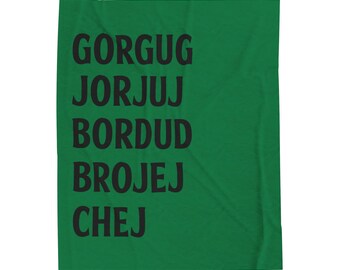 May include: Green throw blanket with black text that reads "Gorgug, Jorjuj, Bordud, Brojej, Chej".
