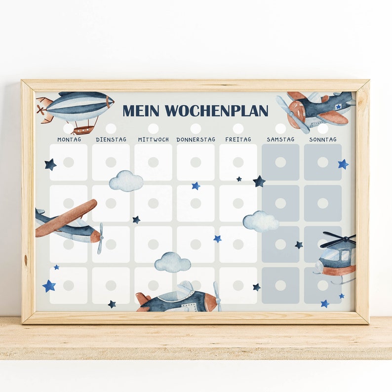 Op de afbeelding: Een blauwe en witte weekplanner met de titel "Mein Wochenplan" en afbeeldingen van vliegtuigen, helikopters en wolken. De planner heeft zeven kolommen voor elke dag van de week, met ruimte voor stickers of markers.