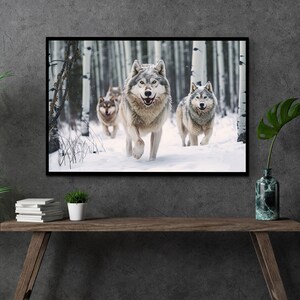 May include: Framed print featuring a pack of wolves running through a snowy forest. The wolves have gray and white fur, with a backdrop of white birch trees. The artwork is displayed on a dark gray wall above a wooden table.