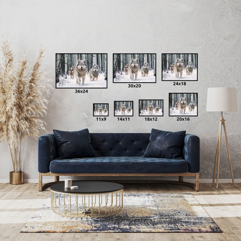 May include: A collection of framed art prints featuring a pack of wolves running through a snowy forest. The prints vary in size, with the largest measuring 36x24 inches and the smallest 11x9 inches. The artwork is displayed above a blue sofa.