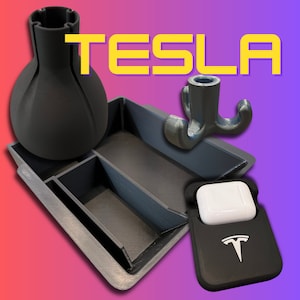 Peut inclure: Ensemble d'accessoires imprimés en 3D, comprenant un vase, un plateau compartimenté, un crochet et un étui pour écouteurs. L'étui porte le logo Tesla. Le mot "TESLA" est affiché en lettres jaunes.