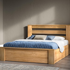 May include: A wooden bed frame with a slatted headboard and a storage drawer underneath. The bed is made with a blue and white patterned bedspread and pillows.
