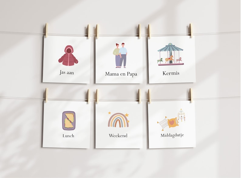 May include: A series of square cards hanging from a string with wooden clips. Each card features a different illustration and text. The illustrations include a coat, a couple, a carousel, a sandwich, a rainbow, and pillows. The text includes the words "Jas aan", "Mama en Papa", "Kermis", "Lunch", "Weekend", and "Middagdutje".