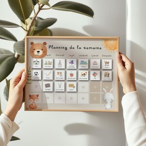 Puede incluir: Un planificador semanal con marco de madera con una ilustraci&oacute;n de oso, zorro y conejo. El planificador tiene un fondo beige claro con iconos ilustrados para cada d&iacute;a de la semana. El texto "Planning de la semaine" est&aacute; en la parte superior.