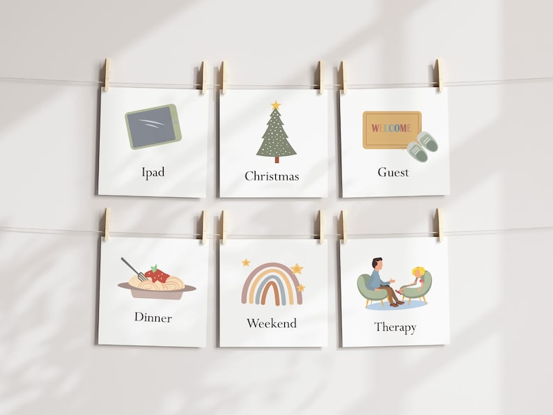 May include: A series of six square cards hanging from a string with wooden clips. Each card features a simple illustration and a word: Ipad, Christmas, Guest, Dinner, Weekend, and Therapy. The cards are against a white background.