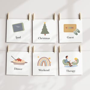 May include: Six square cards hanging from a string with wooden clips. Each card has a different illustration and text: iPad, Christmas, Guest, Dinner, Weekend, and Therapy. The illustrations are simple and colorful, with a minimalist style.