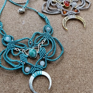 May include: Two macrame necklaces with crescent moon pendants. One necklace is teal with a turquoise stone and the other is beige with a carnelian stone.
