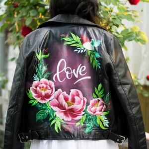 Puede incluir: Chaqueta de cuero negra con un dise&ntilde;o pintado a mano con flores rosas, hojas verdes y la palabra "love" en escritura blanca.