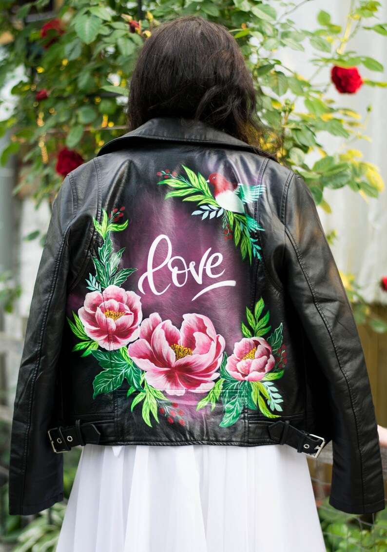 Puede incluir: Chaqueta de cuero negra con un dise&ntilde;o pintado a mano con flores rosas, hojas verdes y la palabra "love" en escritura blanca.