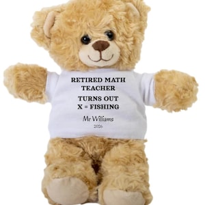 May include: A plush teddy bear with light brown fur, wearing a white t-shirt. The shirt has black text that reads "RETIRED MATH TEACHER TURNS OUT X = FISHING" with the name "Mr Williams" and the year "2026" below.