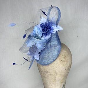 May include: A light blue fascinator with a white netting and blue flower accents.