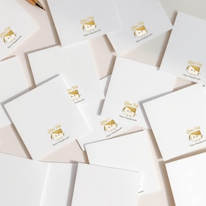 a collection of white square cards or envelopes, each with a gold-colored illustration and text printed on them.