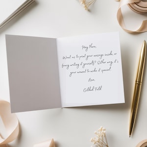 a white card with a handwritten message, a pen, and some decorative elements such as a ribbon and flowers.