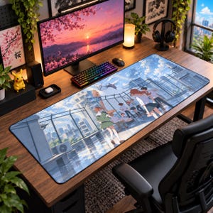 May include: A rectangular desk mat featuring an anime-style illustration of a group of students standing on a rooftop overlooking a city skyline. The scene includes a chain-link fence, blue sky with clouds, and buildings, rendered in shades of blue.