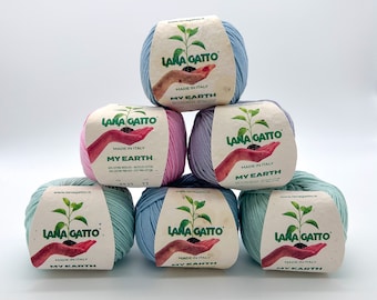 May include: Six balls of yarn in various pastel colors, including light blue, pink, and green. Each ball has a label that reads "Lana Gatto" and "My Earth" in green lettering. The yarn is made in Italy.