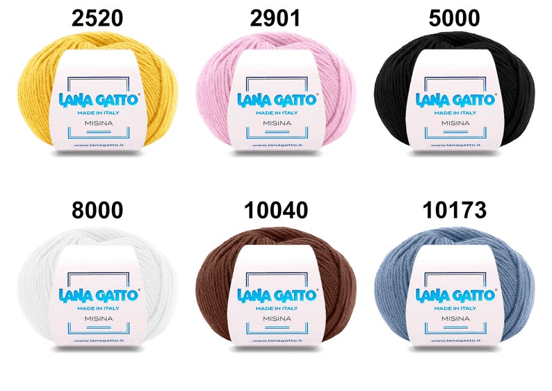 Op de afbeelding: Zes bollen garen in verschillende kleuren, waaronder geel, roze, zwart, wit, bruin en blauw. Elke bol heeft een label met de tekst "Lana Gatto" en "Made in Italy".