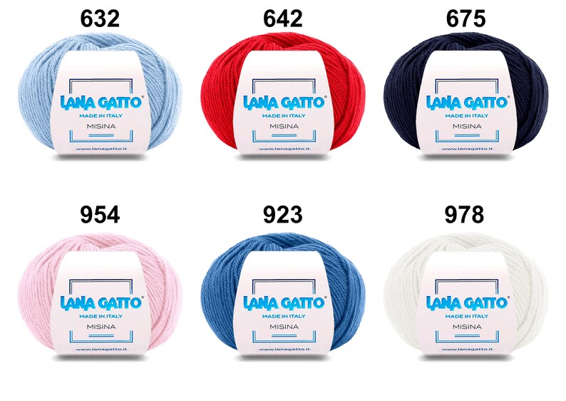 Op de afbeelding: Zes bollen garen in verschillende kleuren: lichtblauw, rood, donkerblauw, roze, blauw en wit. Elke bol heeft een label met de tekst "Lana Gatto" en "Made in Italy" met het nummer van de kleur bovenaan.