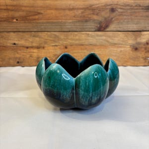 以下が含まれることがあります： ユニークな花びらのようなデザインのセラミックボウル。ボウルは深いティール色で、光沢のある仕上がりです。内側はより濃いティール色で、印象的なコントラストを生み出しています。ボウルの直径は約15cmです。