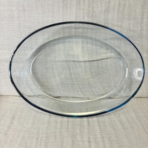 May include: A clear glass oval baking dish with a blue rim.