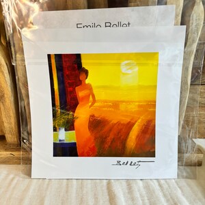 May include: A signed print of a painting by Emilio Rollet. The painting features a woman in a long, flowing dress standing in front of a window with a view of a sunset over a landscape. The painting is in a yellow, orange, and red color scheme.