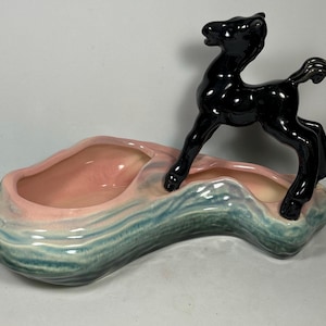 May include: A vintage ceramic planter with a green and pink glaze. A black ceramic horse figurine stands on top of the planter.