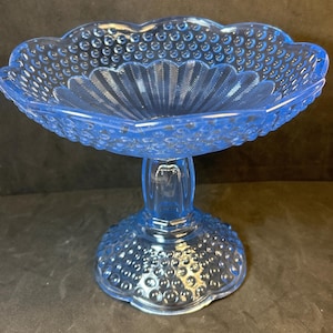 May include: A light blue glass pedestal bowl with a textured, bubbled surface. The bowl has a scalloped edge and a pedestal base.