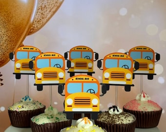 May include: Yellow school bus cupcake toppers with blue windows and the words "School Bus" on the front. The toppers are on cupcakes with various colored frosting and sprinkles.