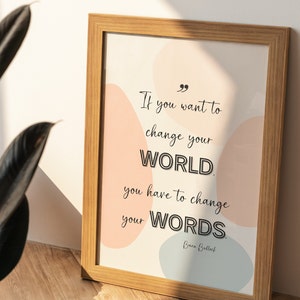 May include: A framed print with a motivational quote: "If you want to change your WORLD, you have to change your WORDS." - Brian Bullock. The quote is printed in black on a white background with abstract shapes in pink and blue.