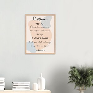 Peut inclure: Une affiche encadrée avec un fond bleu clair et pêche, sur laquelle est imprimé une citation motivante sur la résilience. La citation dit : "Lorsque l'échec frappe à notre porte, la résilience est la réponse qui dit. Je ne serai pas vaincu. Je vais grandir, m'adapter et émerger plus fort que jamais."