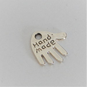 May include: Silver hand charm with the word "Hand Made" engraved on it.