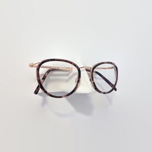 May include: Tortoise shell eyeglasses with gold metal frames and clear lenses.