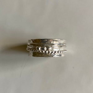 May include: A silver spinning ring with a hammered texture and a beaded band.