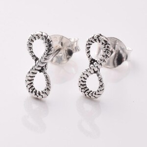 May include: A pair of silver infinity symbol earrings with a textured rope design.