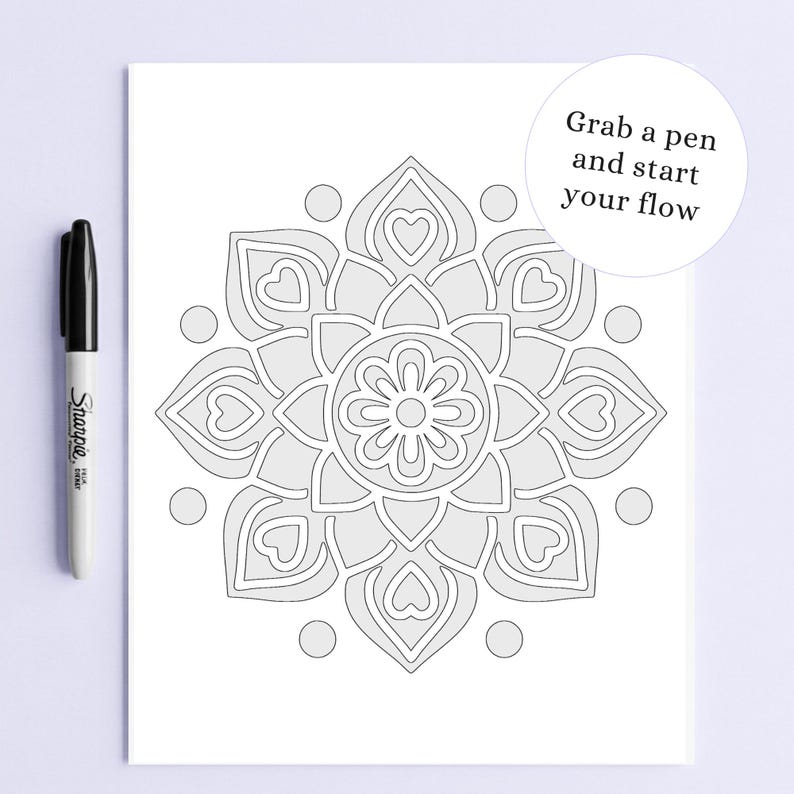 May include: A black Sharpie marker next to a grayscale mandala coloring page with a floral design and heart shapes. The text "Grab a pen and start your flow" is in a white circle.