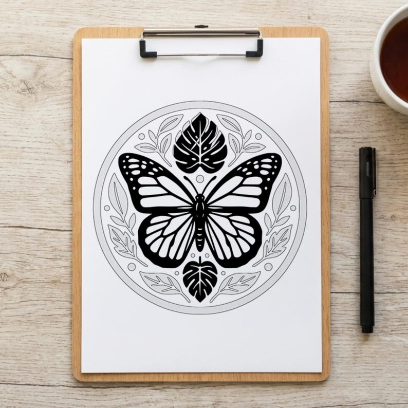 May include: A black and white butterfly illustration on a white paper, clipped to a wooden clipboard. The butterfly is surrounded by leaves and a circular border. A black pen and a white mug are on the wooden surface.