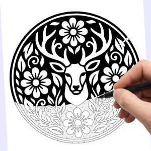 May include: Black and white deer and floral design. The image features a detailed illustration of a deer head with large antlers, surrounded by flowers and leaves. The design is circular and is being colored with a black pen.